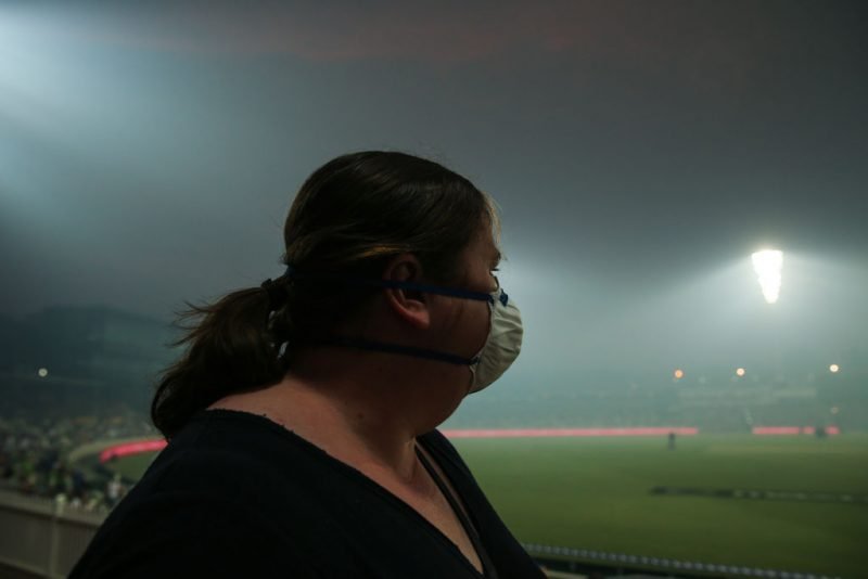 A supporter at the Manuka Oval wears a face mask to stop smoke inhalation